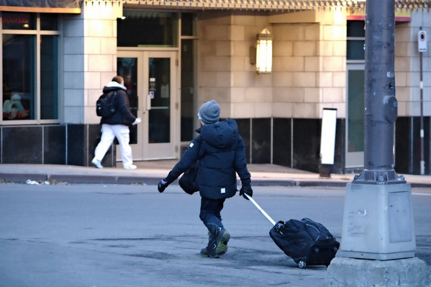 Zwei Personen gehen auf einer kalten Stadtstraße mit einem modernen Gebäude.